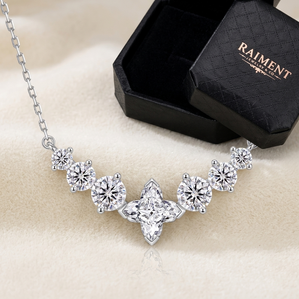 Raiment Jewelry & Co. moissanite chevron cluster necklace beside open jewelry box on cream background