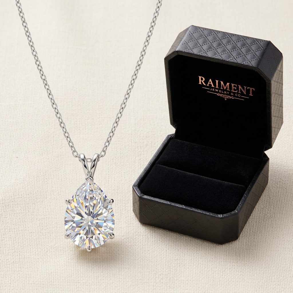 Raiment Jewelry & Co. moissanite teardrop pendant necklace beside open jewelry box on cream background