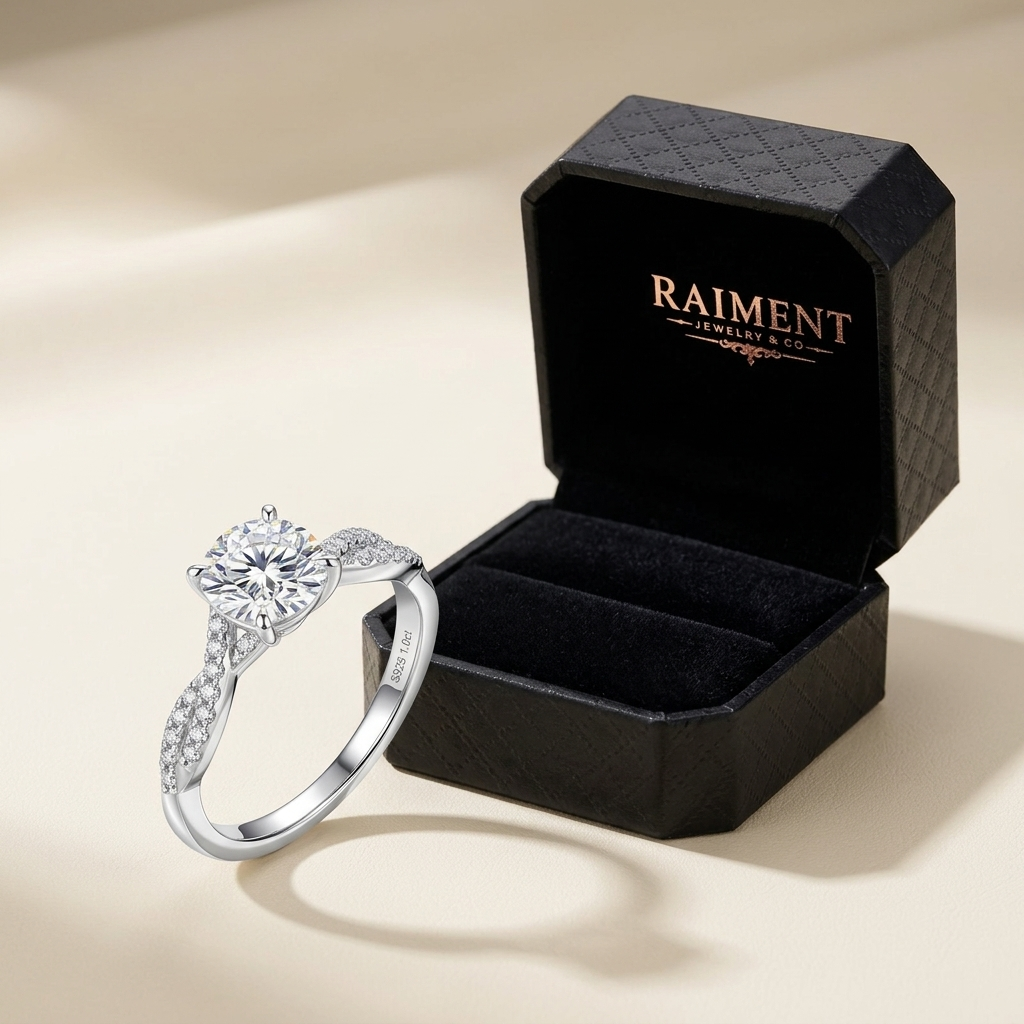 Moissanite 4-claw solitaire ring styled beside jewelry box on cream, Raiment Jewelry & Co.