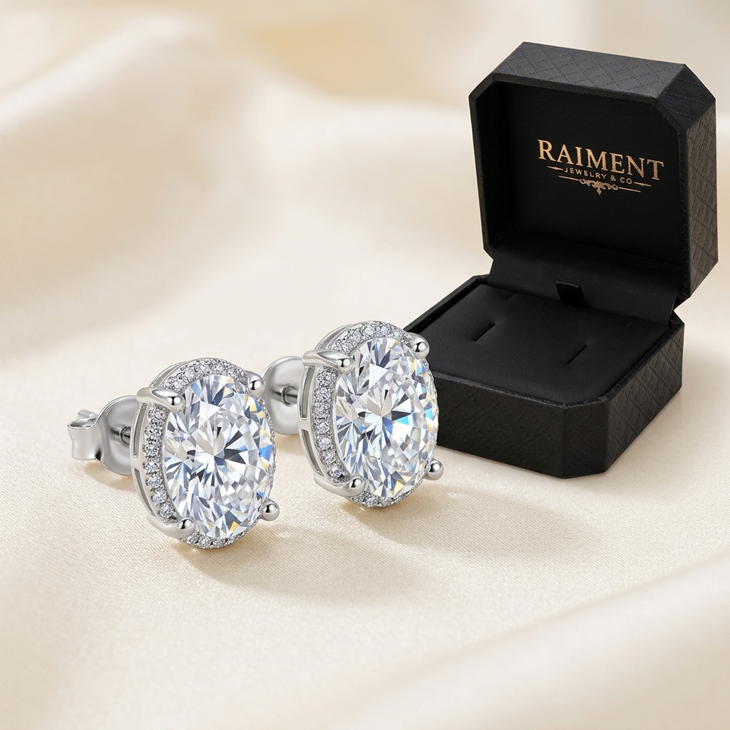 Raiment Jewelry & Co. moissanite oval halo stud earrings beside open jewelry box on cream background