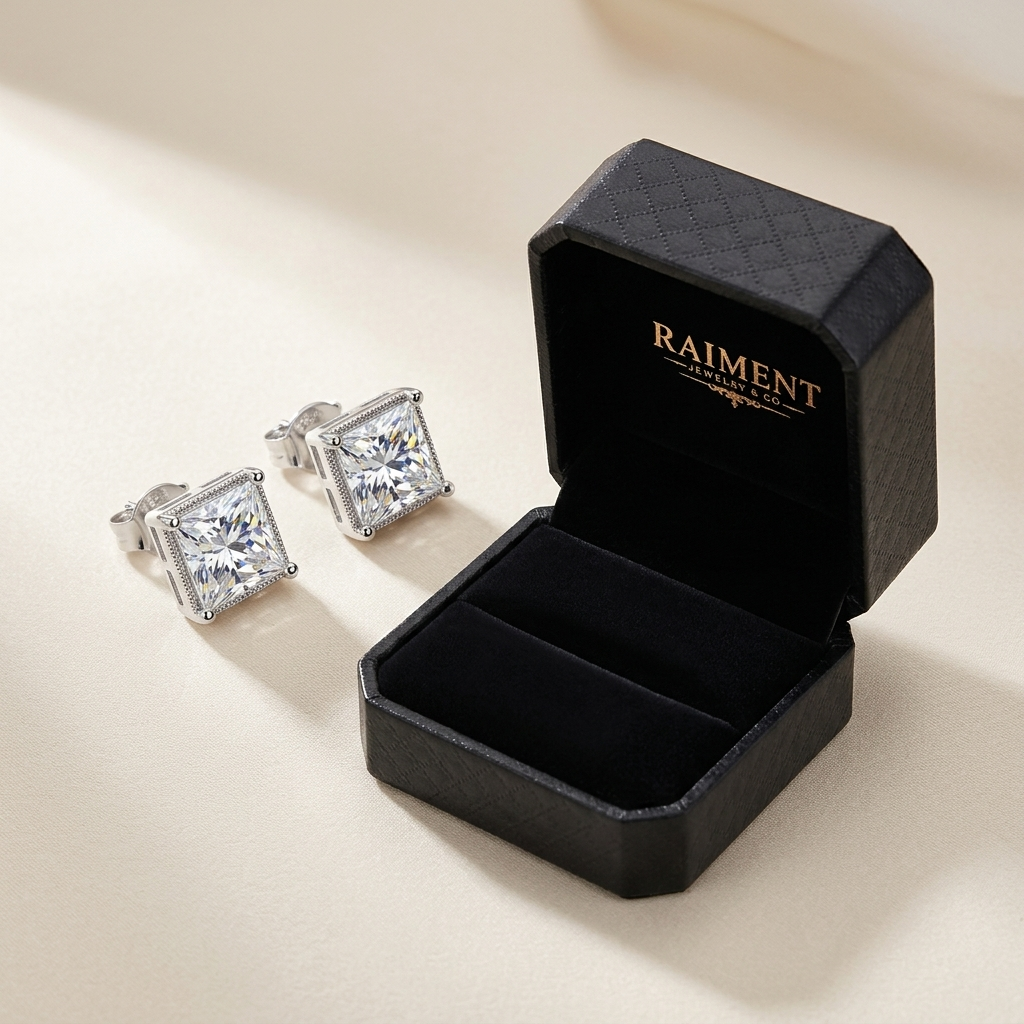 Moissanite princess halo stud earrings styled beside jewelry box on cream, Raiment Jewelry & Co.