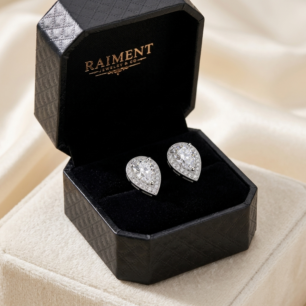 Moissanite pear halo stud earrings inside open jewelry box, Raiment Jewelry & Co.