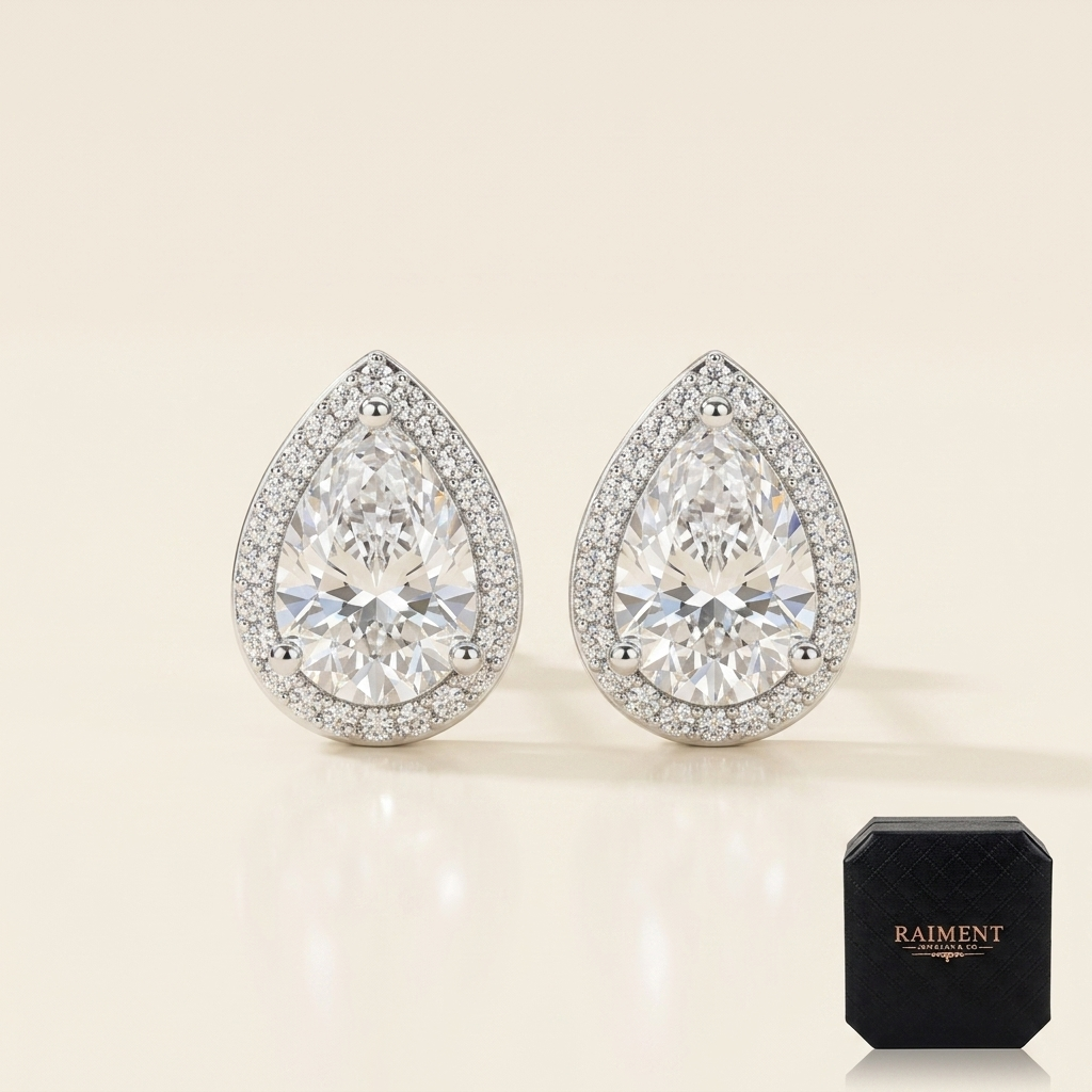 Moissanite pear halo stud earrings on cream background, Raiment Jewelry & Co.