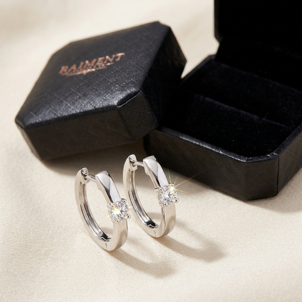 Raiment Jewelry & Co. moissanite slim huggie hoop earrings beside open jewelry box on cream background