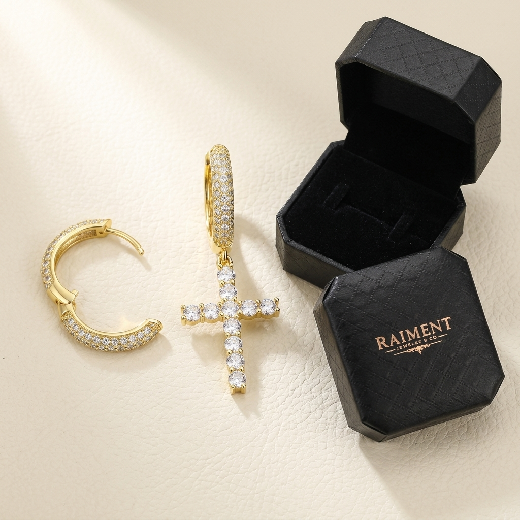 Moissanite cross huggie earrings styled beside jewelry box on cream, Raiment Jewelry & Co.