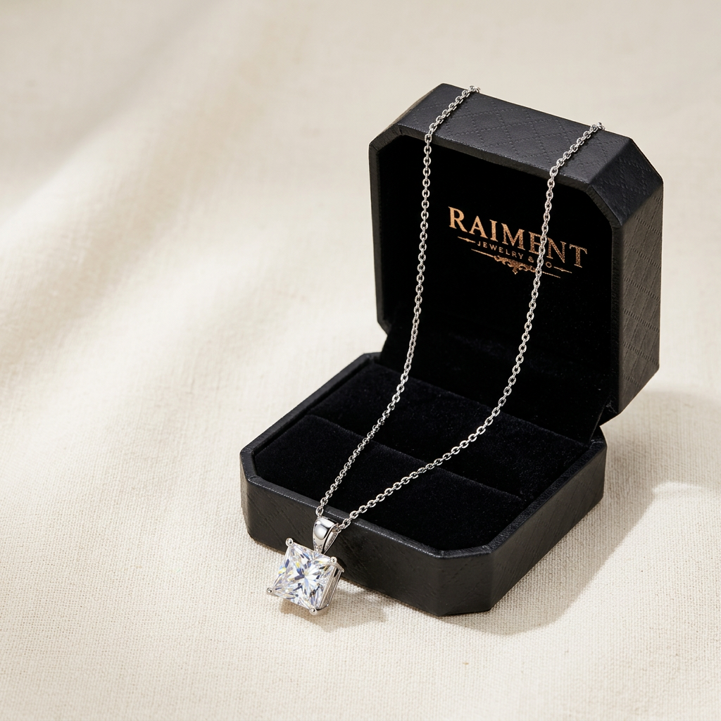 Raiment Jewelry & Co. princess cut moissanite pendant beside open jewelry box on cream background