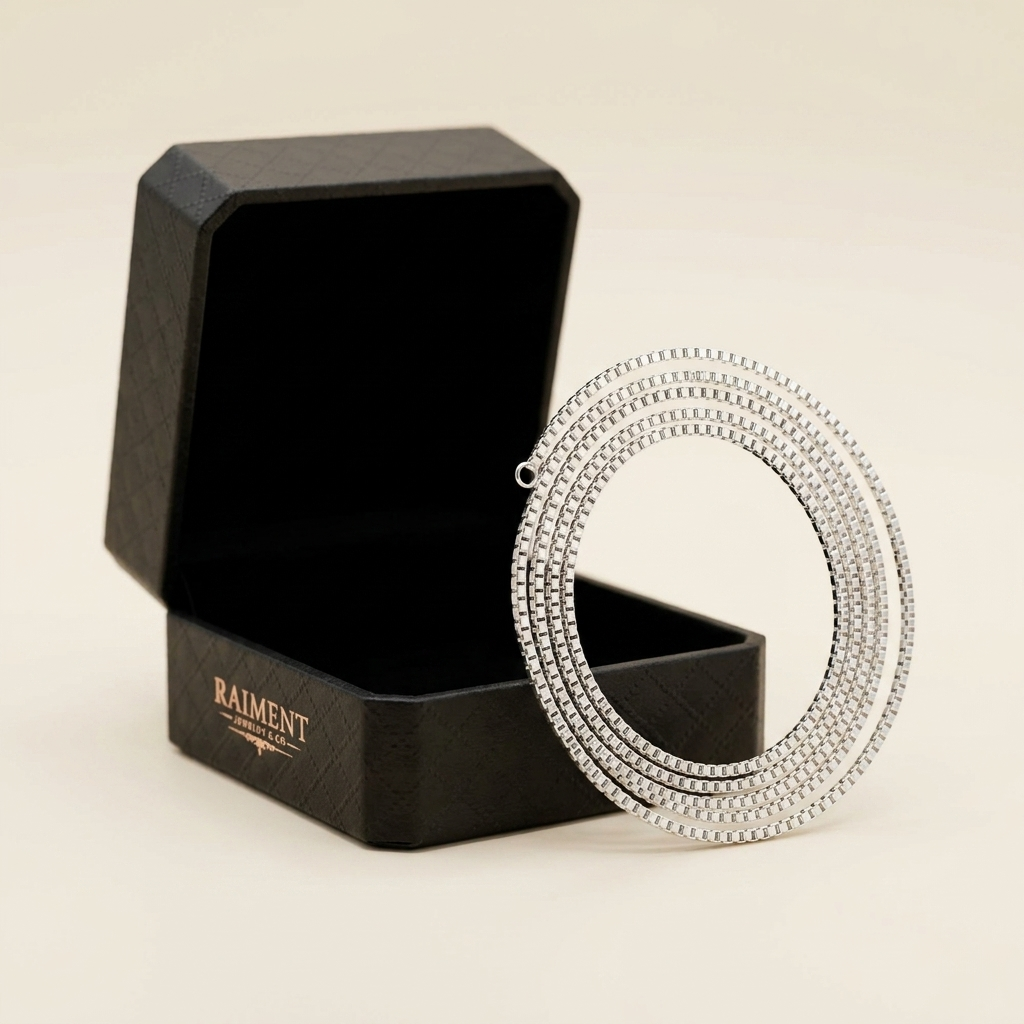 Raiment Jewelry & Co. sterling silver box chain beside open jewelry box on cream background