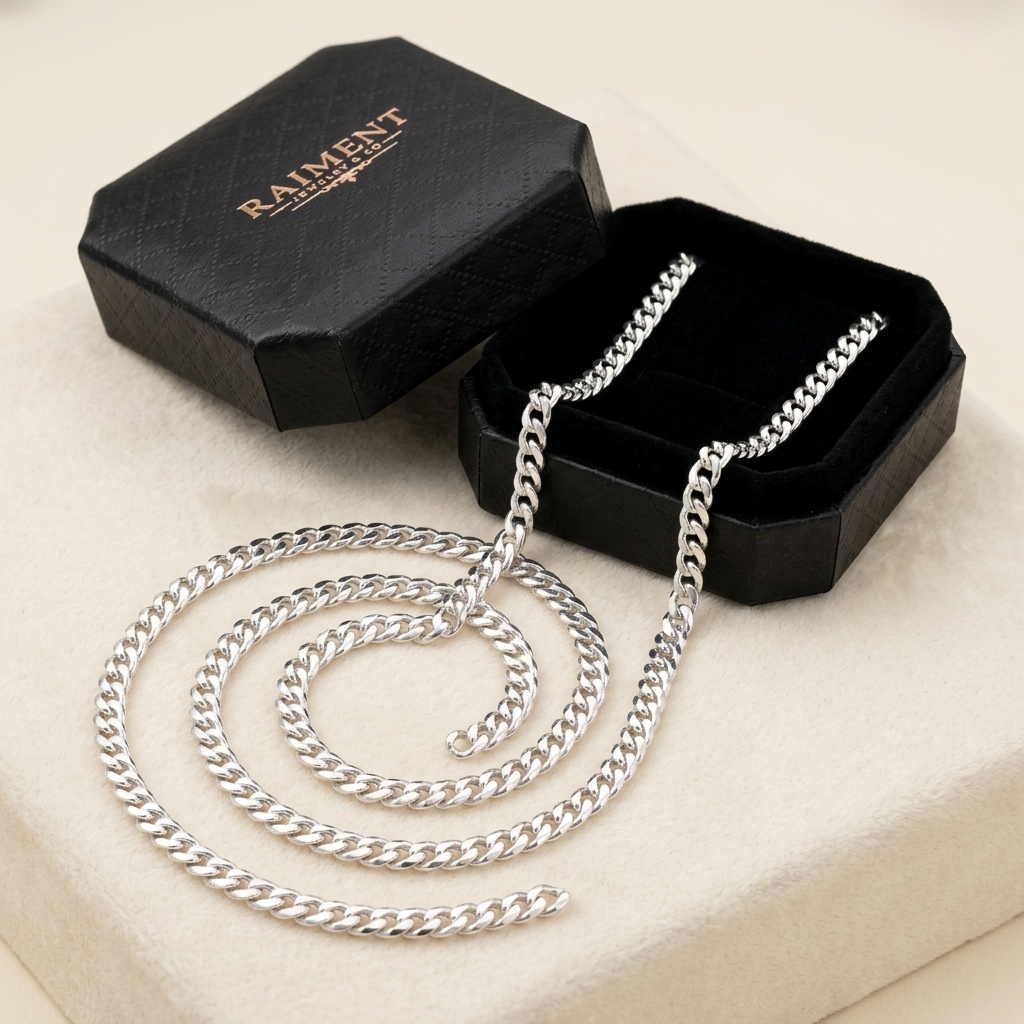 Raiment Jewelry & Co. sterling silver Cuban link chain beside open jewelry box on cream background