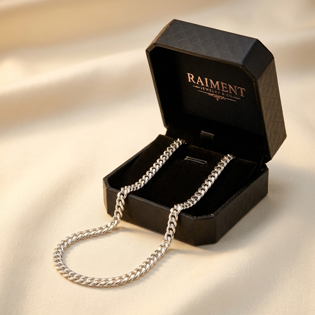 Sterling silver Cuban link chain styled beside jewelry box on cream, Raiment Jewelry & Co.